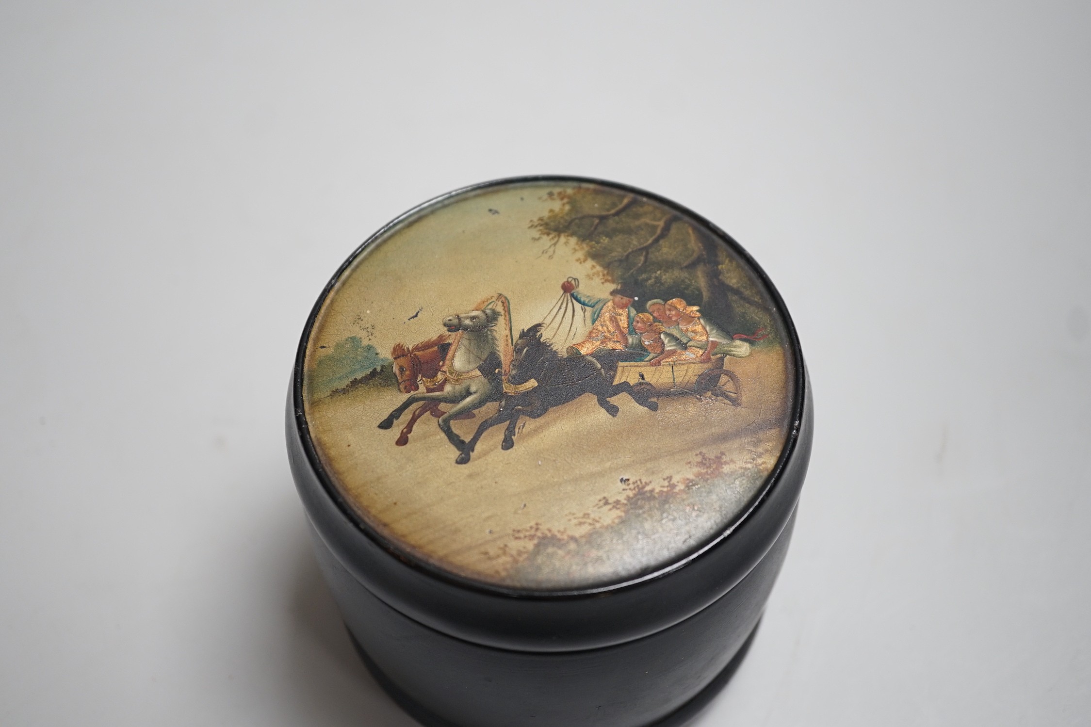 An early 20th century Russian lacquer tobacco box, the cover painted with a winter scene with figures in a troika. 9.5cm high